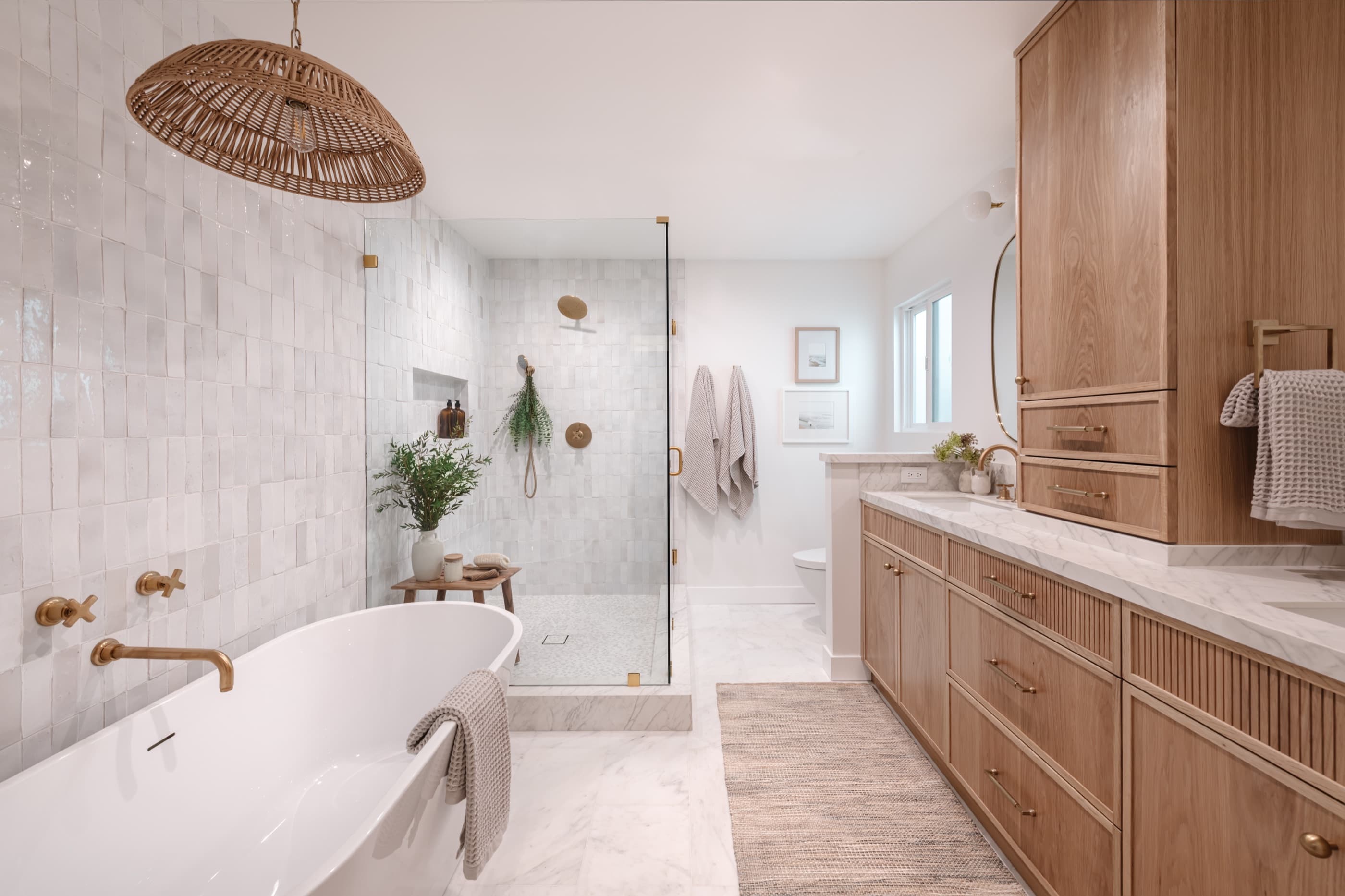 A marble bathroom with a freestanding tub, a zellige-tiled shower and a fluted white-oak vanity.